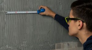 Homme qui mesure avec un mètre pour choisir les dimensions de sa cabine de douche